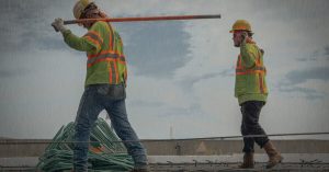 trabalhadores de bota, calça e colete refletivo tendo que parar as atividades por conta da obra com chuvas