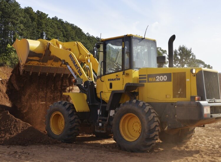 máquina komatsu amarela descarregando em um compartimento exemplo de habilitação para máquinas pesadas